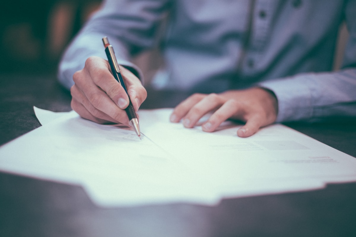 Person signing contract at desk